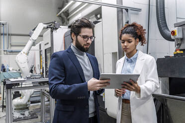 Junger Geschäftsmann diskutiert mit einem Kollegen über einen Tablet-PC in einer Fabrik - AAZF00072