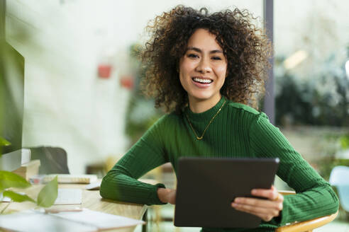 Glückliche Geschäftsfrau mit Tablet-PC am Tisch sitzend - EBSF02764