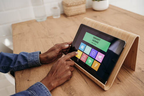 Hände einer Frau, die eine Hausautomatisierungs-App auf einem Tablet-PC benutzt - EBBF07937
