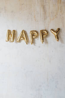 Happy text made with inflated balloons hanging on wall - MEUF08888