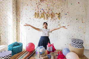 Happy woman enjoying under falling confetti - MEUF08913