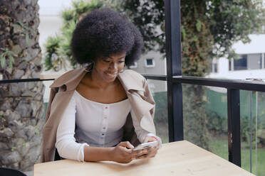 Frau mit Smartphone am Tisch sitzend - DSIF00661