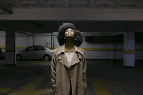 Woman wearing overcoat standing in car park - DSIF00671