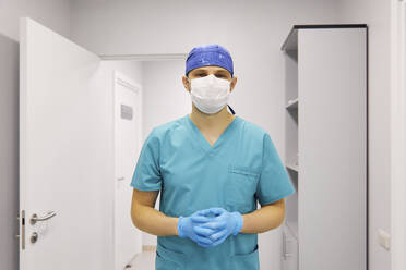 Surgeon wearing protective face mask standing at hospital - SANF00016