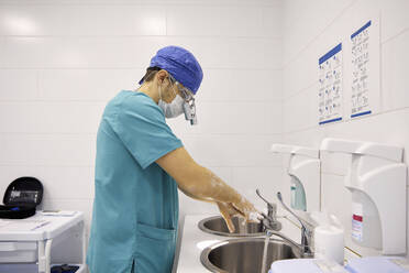 Surgeon washing hands in sink at hospital - SANF00017