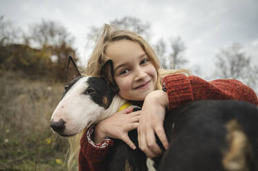 Lächelndes süßes Mädchen umarmt Hund - ALKF00095