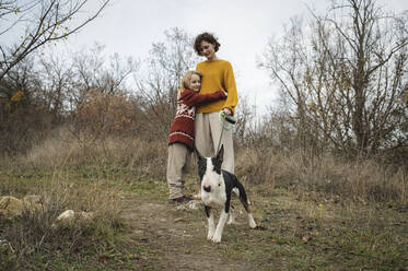 Daughter embracing mother with Bull Terrier dog - ALKF00105