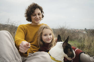 Glückliche Mutter und Tochter sitzen mit Bullterrier-Hund - ALKF00106