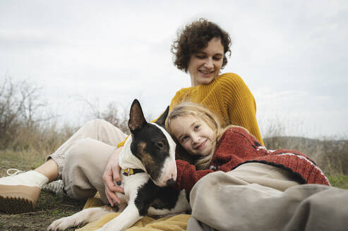Tochter und Mutter entspannen sich mit Hund vor dem Himmel - ALKF00108