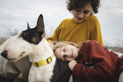 Tochter entspannt auf dem Schoß der Mutter mit Bullterrier-Hund - ALKF00109