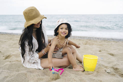 Glücklicher Junge mit Mutter, der am Strand im Sand spielt - JJF00049