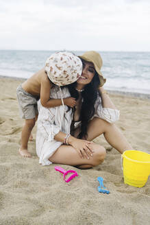 Junge küsst Mutter auf Sand am Strand sitzend - JJF00051