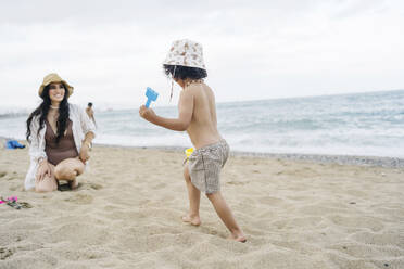 Junge mit Hut läuft seiner Mutter am Strand entgegen - JJF00053