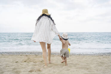 Mutter hält Hände, die auf Sand am Strand spazieren gehen - JJF00054