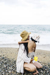 Mother embracing son by sea at beach - JJF00057