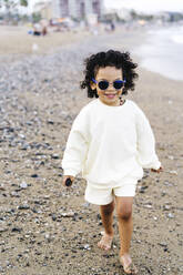 Smiling boy walking on stone at beach - JJF00080