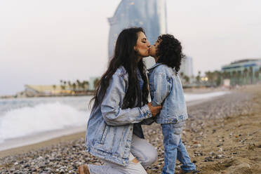 Mother kissing boy on mouth at beach - JJF00085