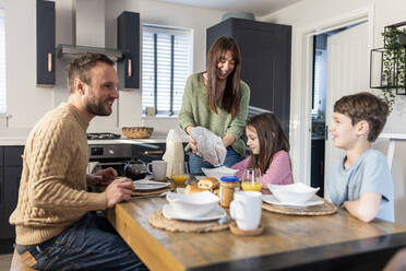 Glückliche Familie beim gemeinsamen Frühstück am Küchentisch - WPEF07197