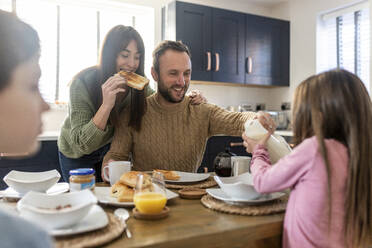 Glücklicher Mann und Frau beim Frühstück mit Kindern in der Küche - WPEF07199