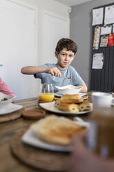 Boy having breakfast at table at home - WPEF07201