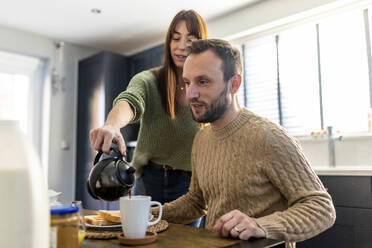 Mann mit Frau, die am Tisch Kaffee in eine Tasse gießt - WPEF07202