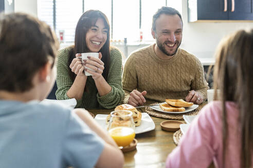 Glückliche Familie beim gemeinsamen Frühstück am Tisch - WPEF07205