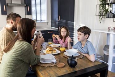 Familie beim gemeinsamen Frühstück in der Küche zu Hause - WPEF07214