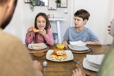 Happy siblings with mother and father having breakfast together at home - WPEF07216