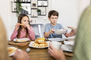 Siblings with mother and father having breakfast together at home - WPEF07217