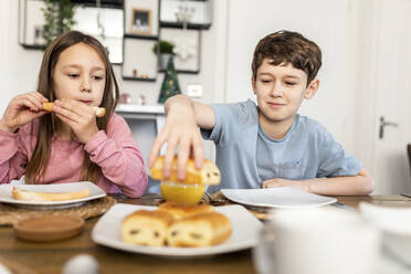 Brother and sister having breakfast at table - WPEF07218