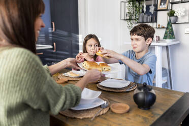 Happy mother serving breakfast to children at table - WPEF07219