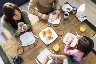 Man and woman having breakfast with children at table - WPEF07221