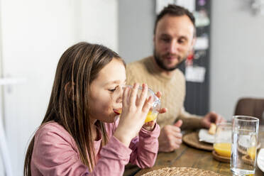 Mädchen trinkt Saft mit Vater beim Frühstück zu Hause - WPEF07226