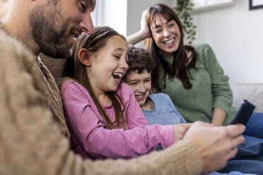 Happy family using mobile phone at home - WPEF07246