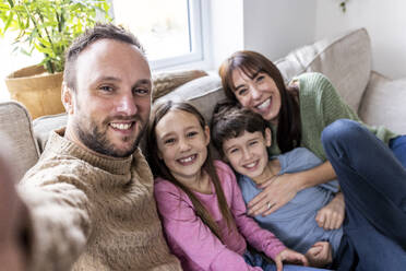 Happy man taking selfie with family at home - WPEF07250