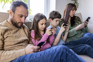 Familie benutzt Smartphone auf dem Sofa zu Hause - WPEF07258