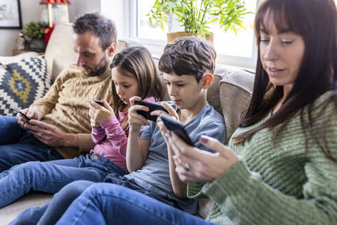 Familie benutzt Mobiltelefon auf dem Sofa zu Hause - WPEF07259