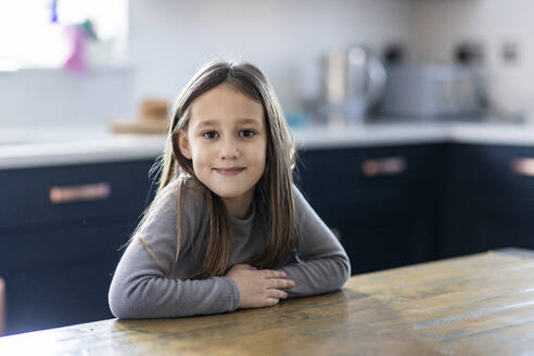 Smiling girl sitting at table in kitchen - WPEF07298