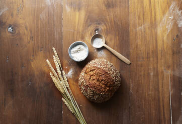 Wheat, flour and freshly baked loaf of bread on wooden table - KSWF02289