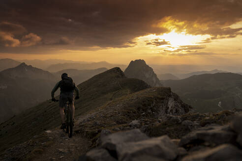 Mann radelt bei Sonnenuntergang auf einem Berg - MALF00420