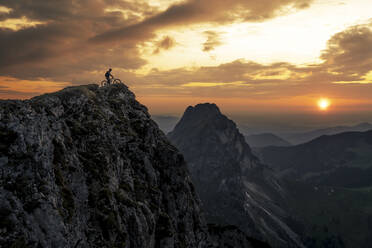 Man with bike on top of mountain at sunset - MALF00422