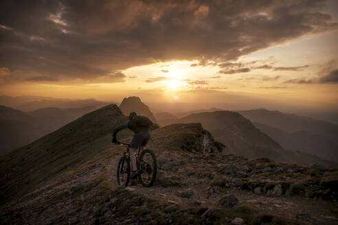 Mann fährt Mountainbike auf einem Wanderweg bei Sonnenuntergang - MALF00426