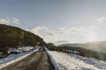 Empty mountain road amidst snow in winter at sunny day - ACPF01550