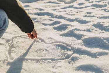 Frau zeichnet Herzform auf Schnee im Winter - ACPF01551