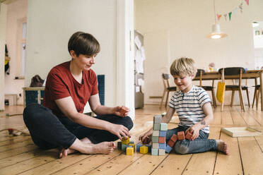 Mother and son playing with toy blocks sitting at home - JOSEF16970