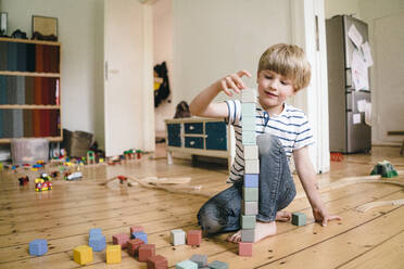 Junge spielt mit Spielzeugblöcken auf dem Hartholzboden zu Hause - JOSEF16985