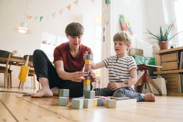 Mother and son balancing toy blocks sitting at home - JOSEF16990