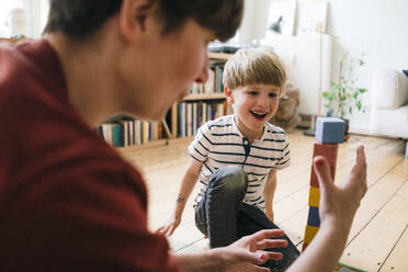 Happy boy playing toy blocks with mother at home - JOSEF16992