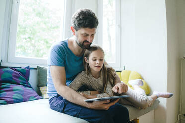 Father sharing tablet PC with daughter at home - JOSEF17034