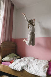 Unbekümmertes Mädchen springt zu Hause auf dem Bett herum - JOSEF17050
